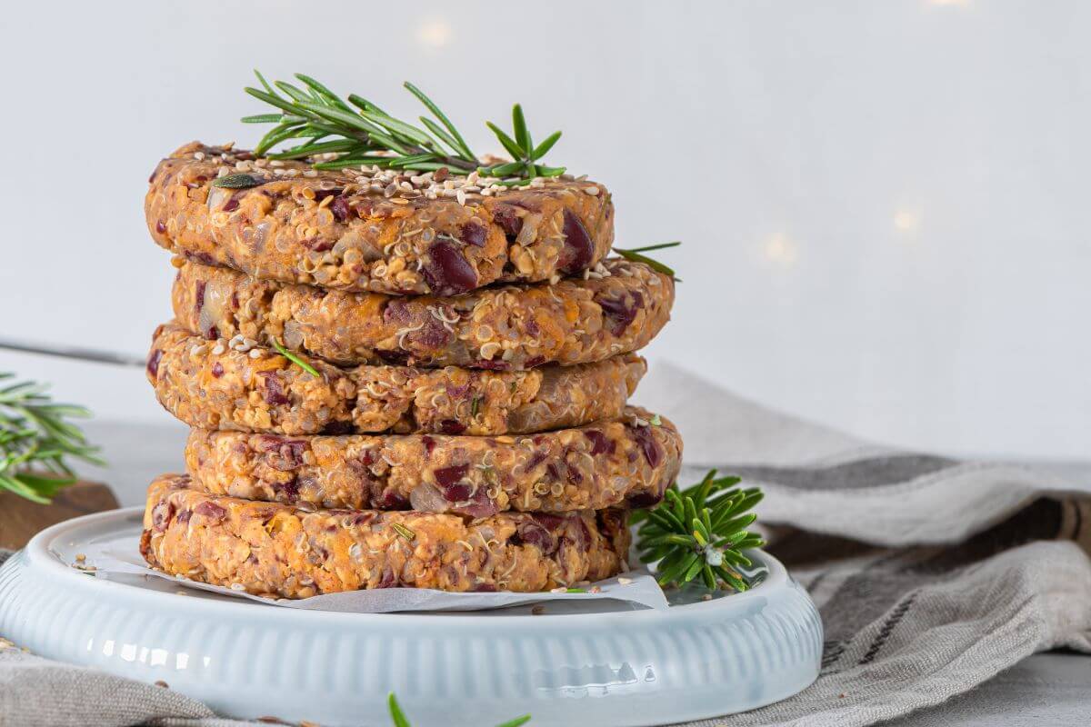The picture shows veggie burger patties on a plate with fabric indicating that plant-based meat substitutes cost significantly more than regular meat, making your own patties at home can also help stretch your grocery budget.