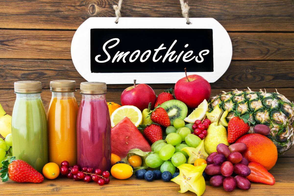 The picture of different types of fruits, a board with a note, and bottles with fruit drinks referring to bottled smoothies come with a high price tag, blending your own at home is cheaper and lets you control the ingredients.