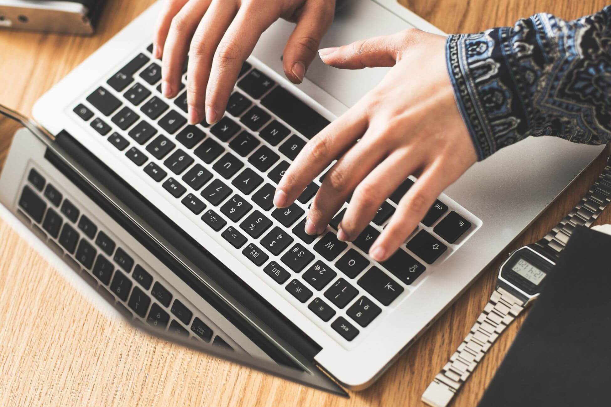 The picture tells about a watch on the table and a girl's hand using a laptop which means using fee apps or templates to stay organized helps you stay on top of spending.