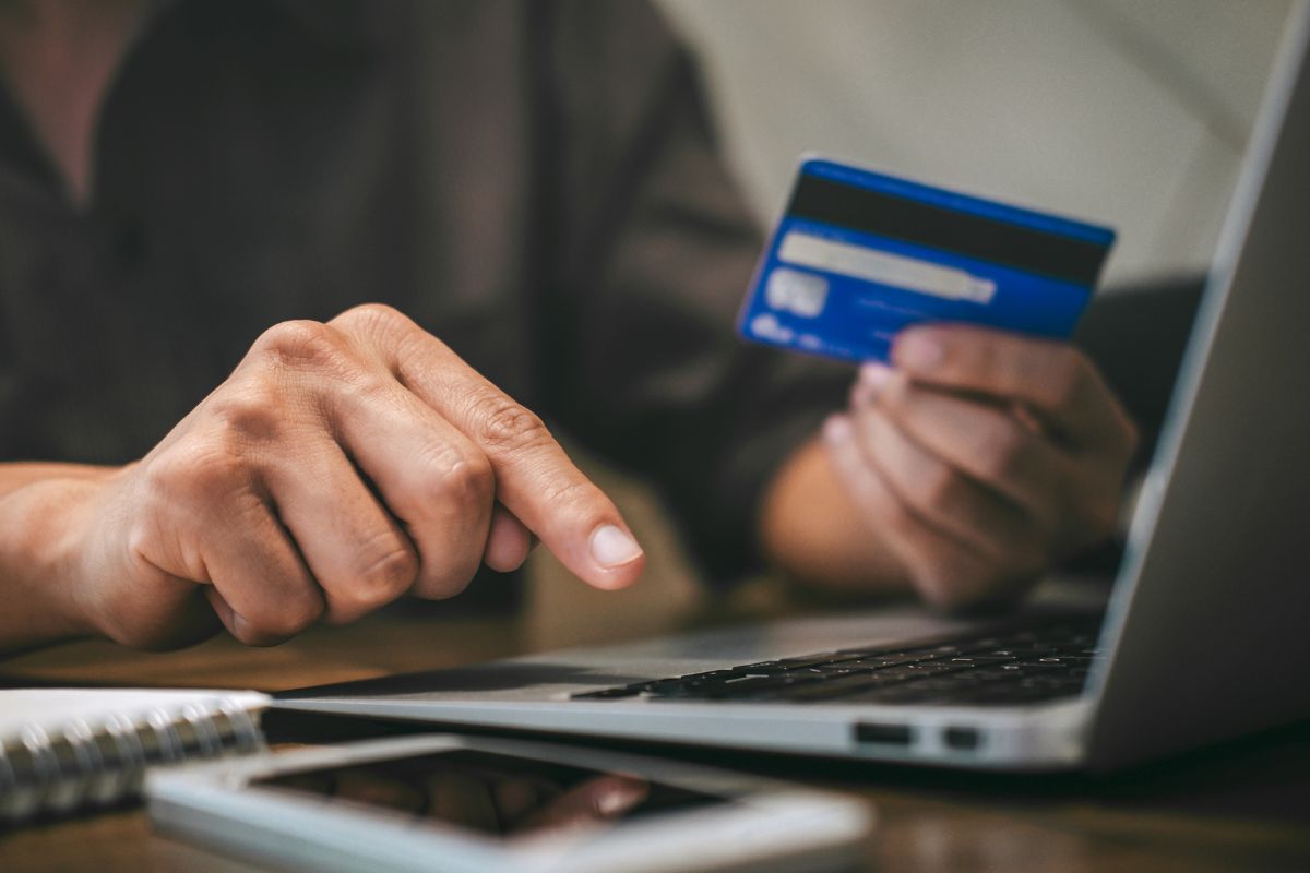 Image of a man's hand using a credit card.