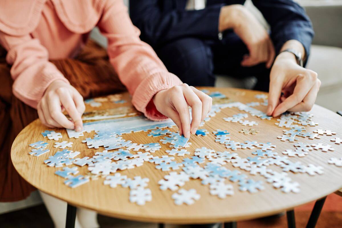 The image shows a couple playing puzzle games together which means a puzzle made from one of your photos together is a fun and creative gift.