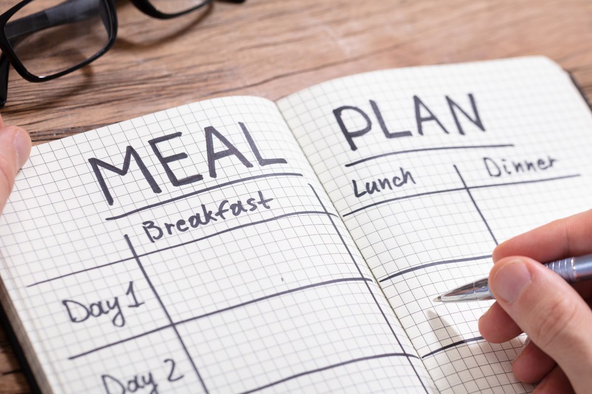 The photo shows a man's hand making a meal plan.