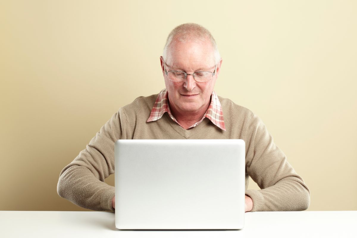 The picture shows a senior man using a laptop.