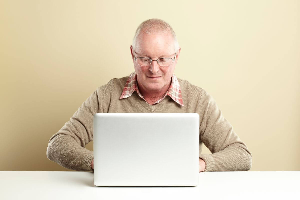 The image tells about a senior using a laptop referring to if they're short on savings, they may need to work part-time to earn extra income and put it into their retirement savings.