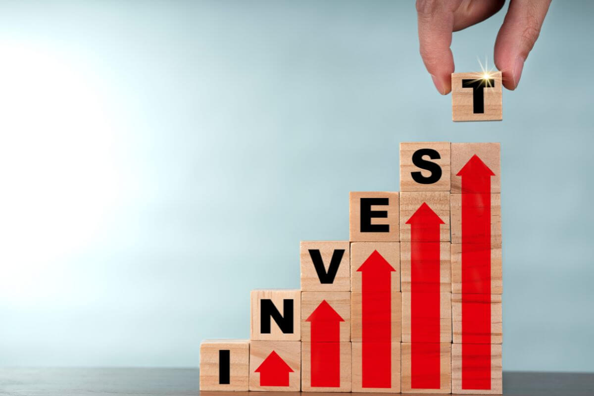The photo tells about cubes with letters and arrows and a man's hand putting the last letter which means investing wisely and reducing debt before retirement can make them financially secure and stable.
