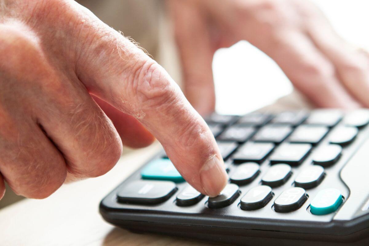The picture shows a senior's hand using a calculator referring to if they're unsure, running a retirement calculator can give them a clearer picture.