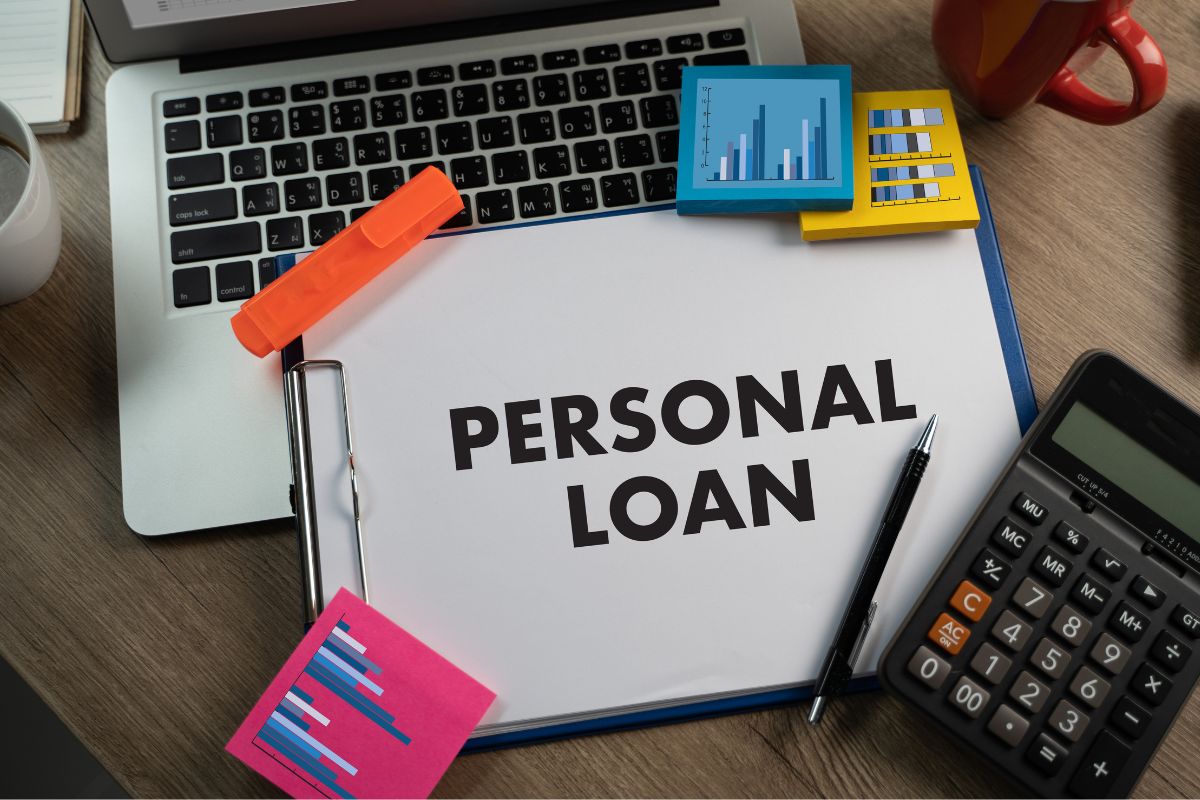 Image of a laptop, a calculator, and a paper with personal loan wording.