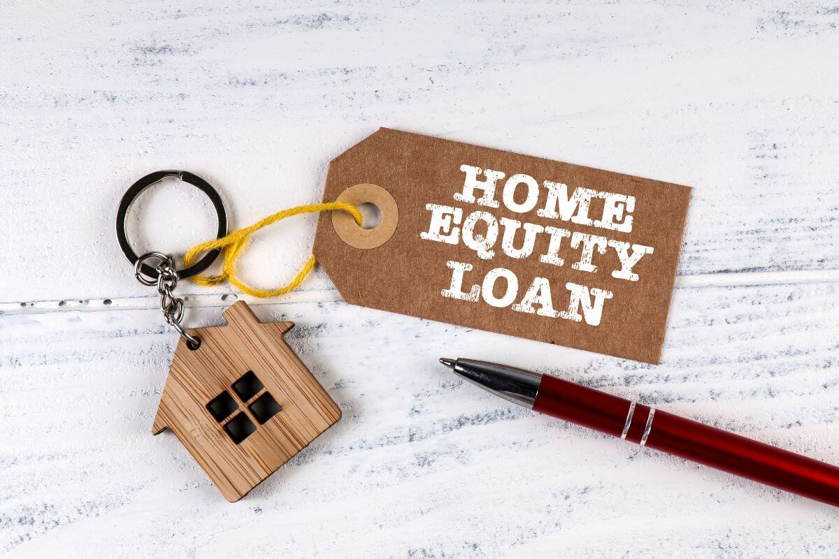 The picture shows a pen, and a house keychain with a tag which means home equity loans can keep your retirement risky, and paying them off ensures your home remains yours without extra financial strain. 