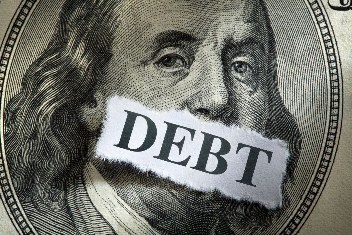 The photo shows a dollar sign and a piece of paper with a note which means a high-interest consumer debt eats away your income and makes it harder to retire comfortably.