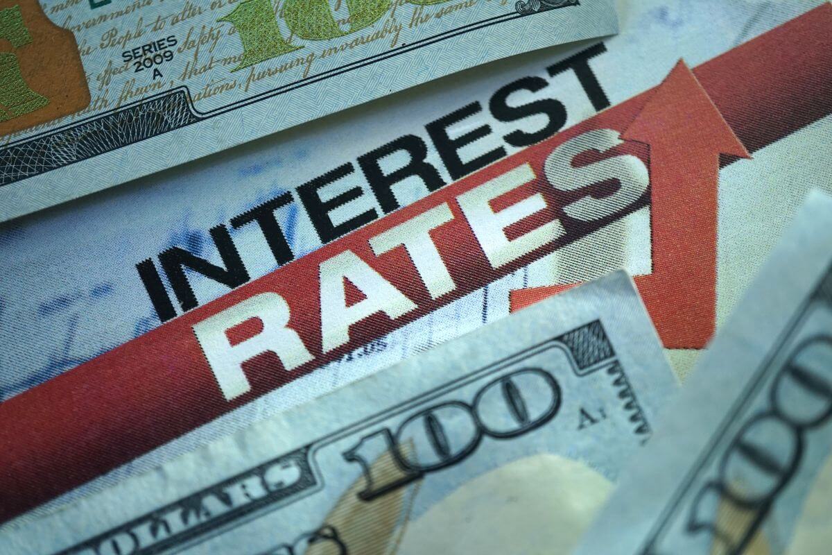 The image shows an up arrow, dollar bills, and notes which means recurring debt with high interest makes retirement harder, paying it off before leaving the workforce means fewer financial surprises.