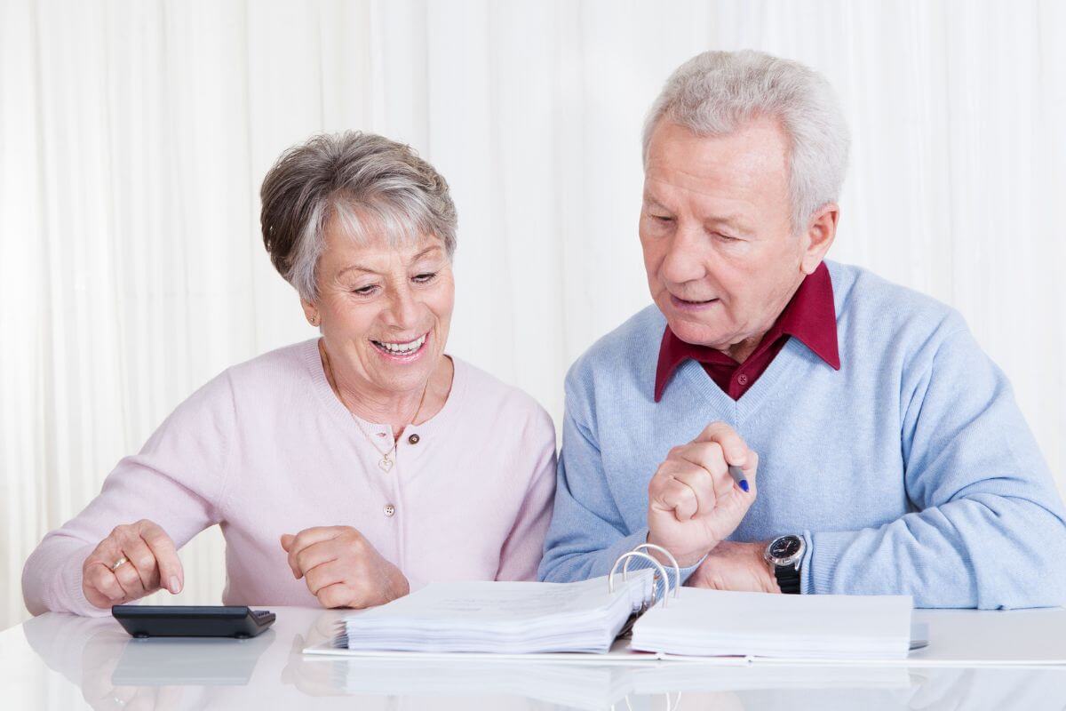 The image shows a senior couple looking at the papers while calculating referring time to budget to pay off debt before retirement helps you pay down what you owe faster.