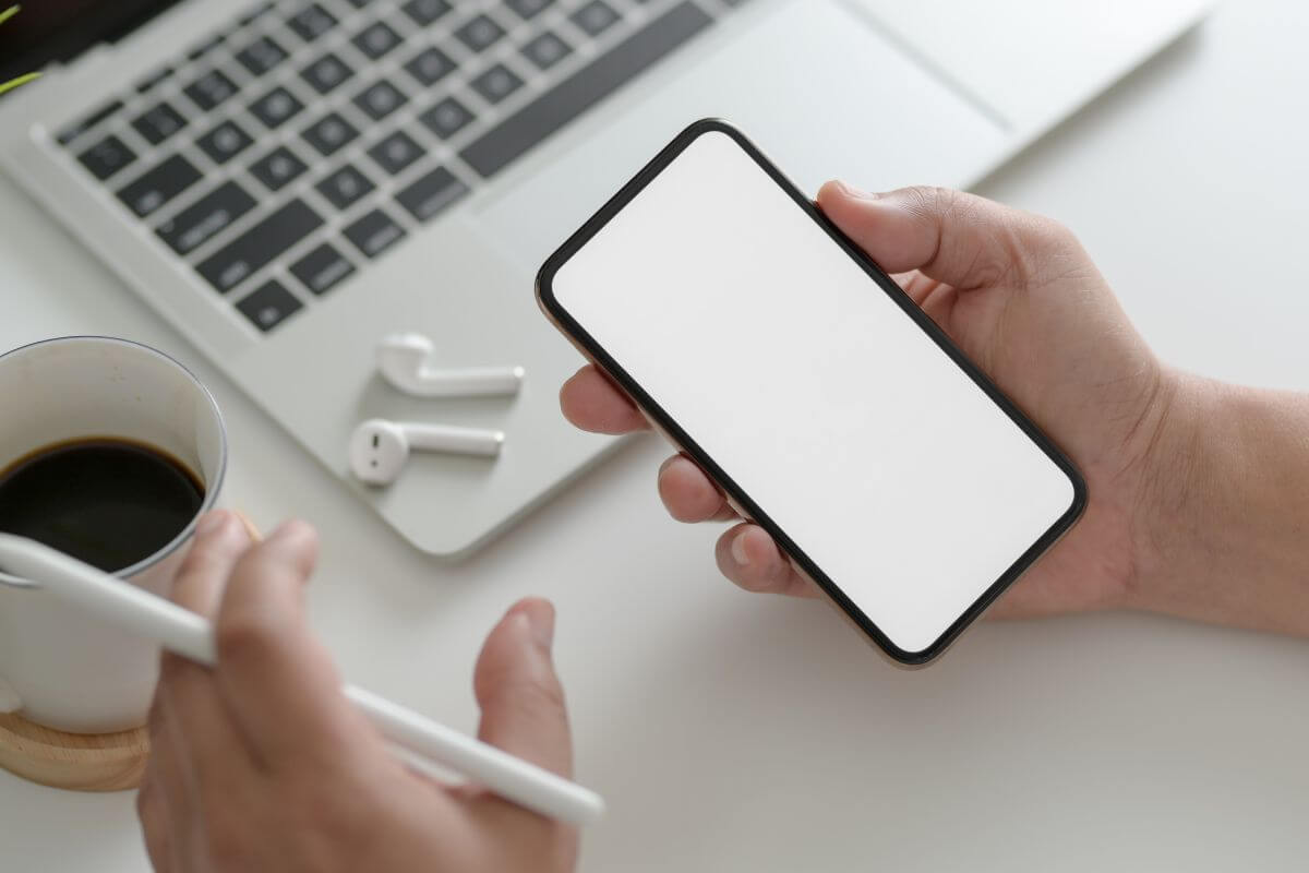 The photo tells about a laptop, a pair of earphones, a coffee, and a girl's hand holding a phone and digital pen which means free resources and apps that can help you learn the basics making it easier to understand.