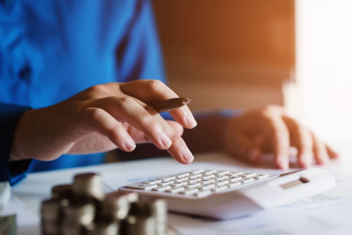 The photo shows coin stocks, papers on the table, and a girl's hand using a calculator referring to budgeting doesn't have to be complicated, using this budgeting method gives you a clear plan without being too restrictive.