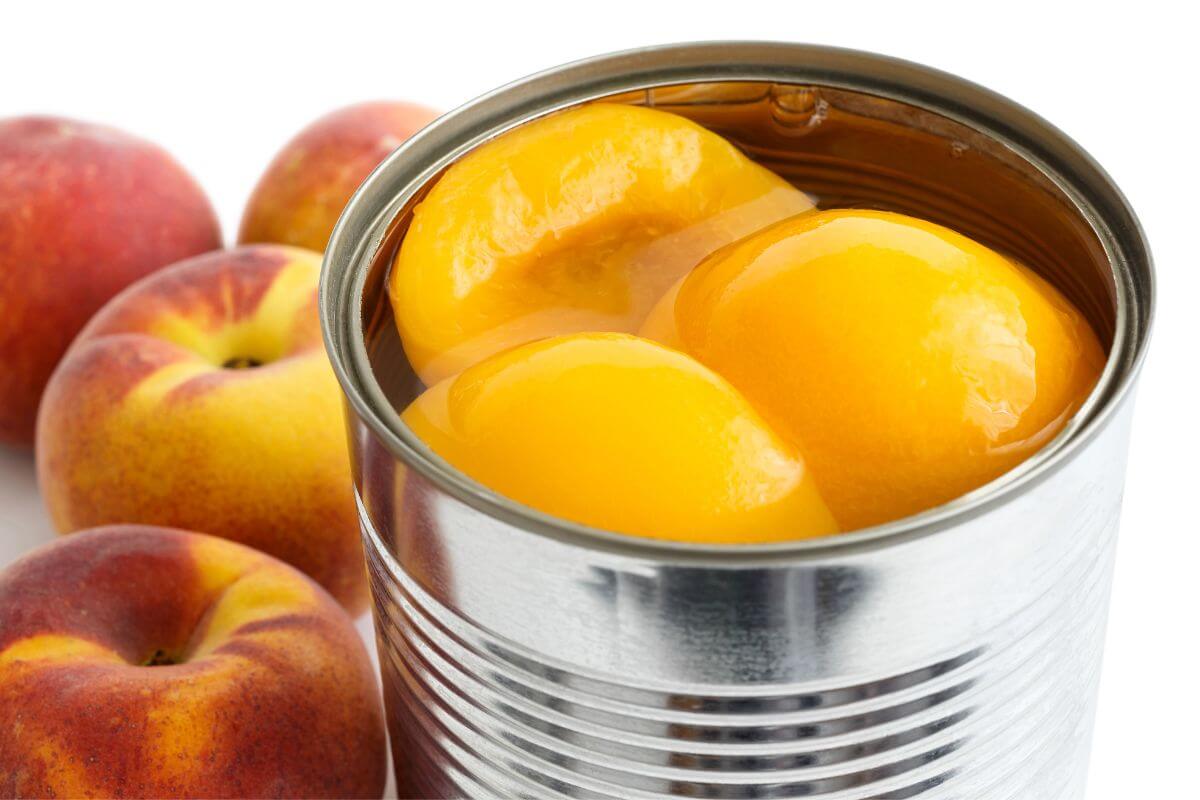 The photo tells about canned fruits like peaches and fresh peaches on the table which is a good way to get vitamins and natural sweetness and a budget-friendly way to keep fruit in your diet year-around.