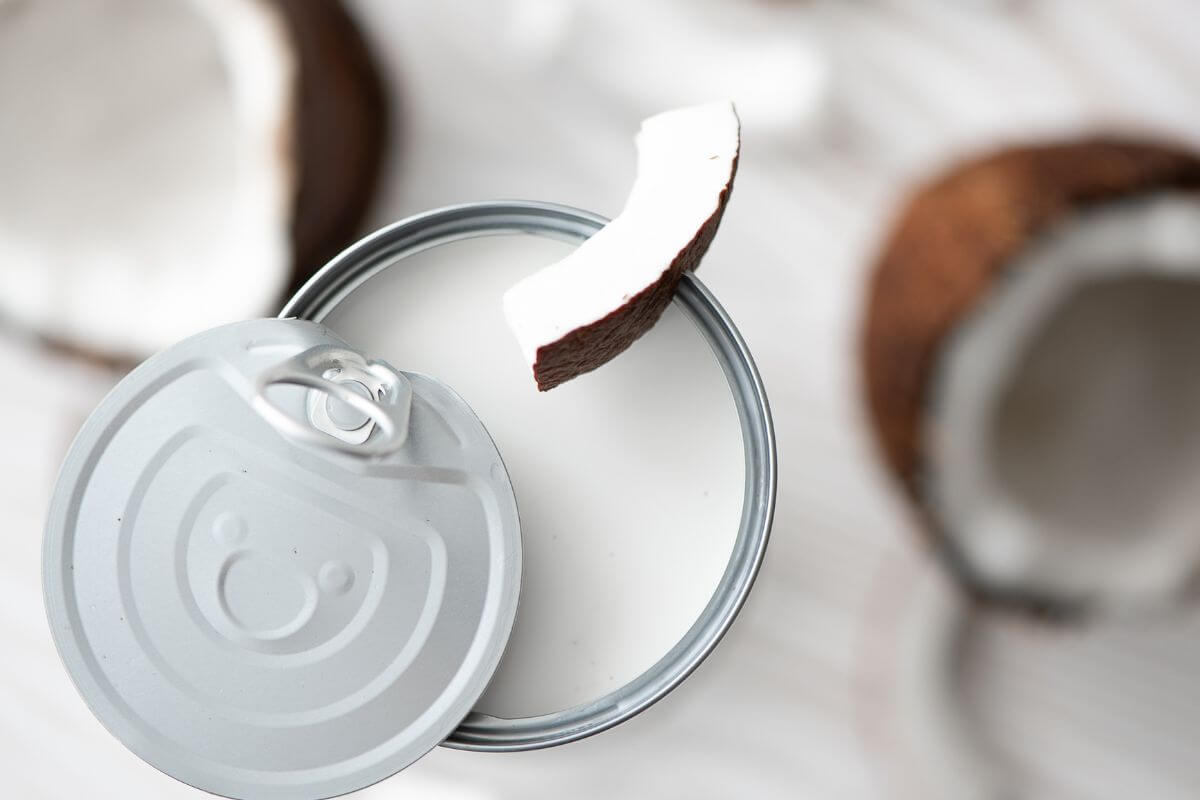 The image shows coconut fruits and canned coconut milk is a great staple for making creamy soups that allow for a variety of flavorful and budget-friendly meals.