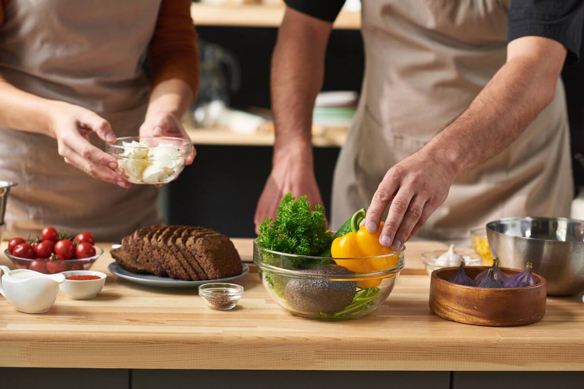 The picture of ingredients on the bowls and a couple preparing them which means cooking a fancy meal at home is a fun way to spend time together while avoiding prices and busy restaurants.