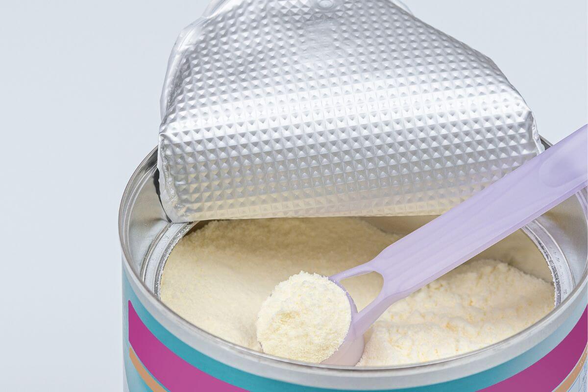 The image shows canned baby food with a scoop which means a quick and reliable food source for babies that lasts longer than freshly made baby food and is easy to store.