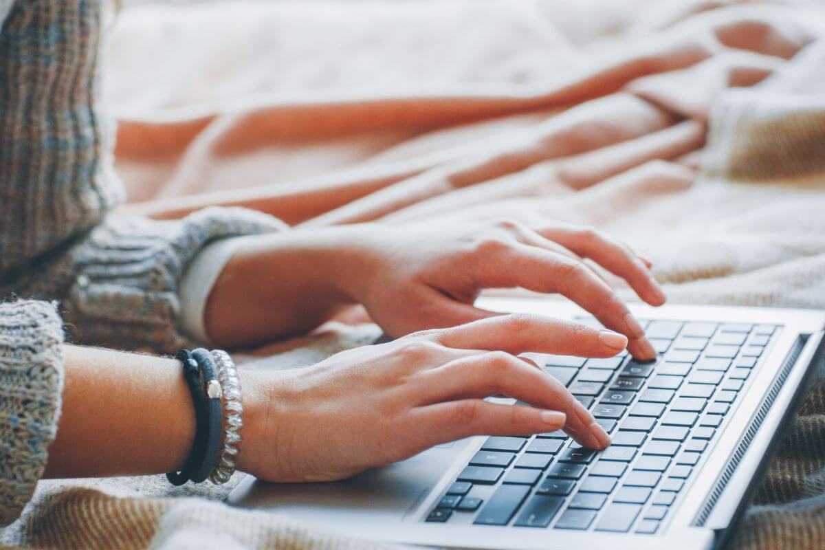 The picture shows a girl's hand using a laptop indicating that freelance writing is a great way to work from home without using your voice.