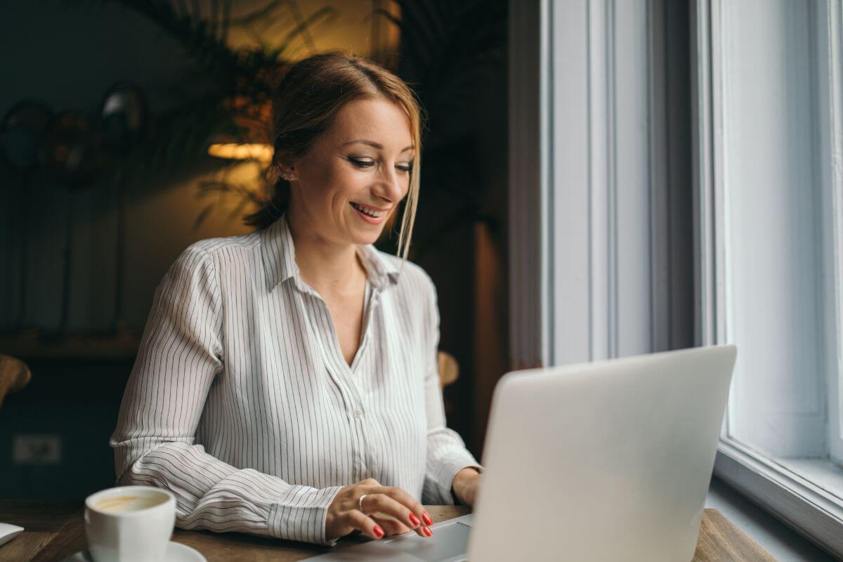 The photo tells about a girl using a laptop while having a coffee referring to a virtual assistant who can make a good income with flexible tasks.