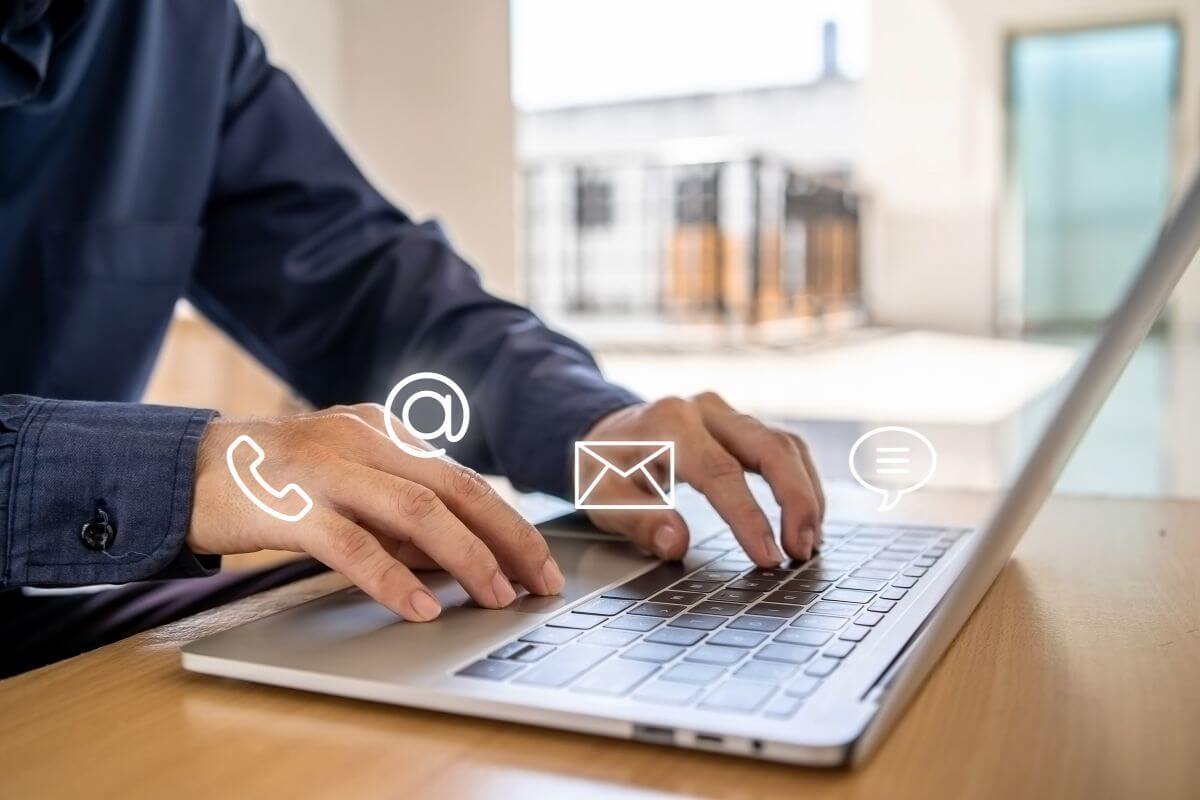 The photo shows a man's hand using a laptop with a screen display of icons referring to remote customer service means you can work from home without talking, just responding to questions in writing.