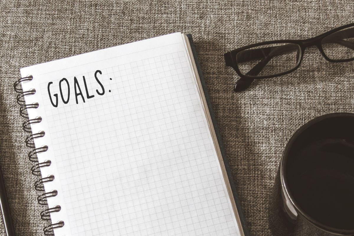 The image shows an eyeglass, a coffee, and a notebook with a note which means no-spend year can be customized based on individual goals that can lead to big savings.