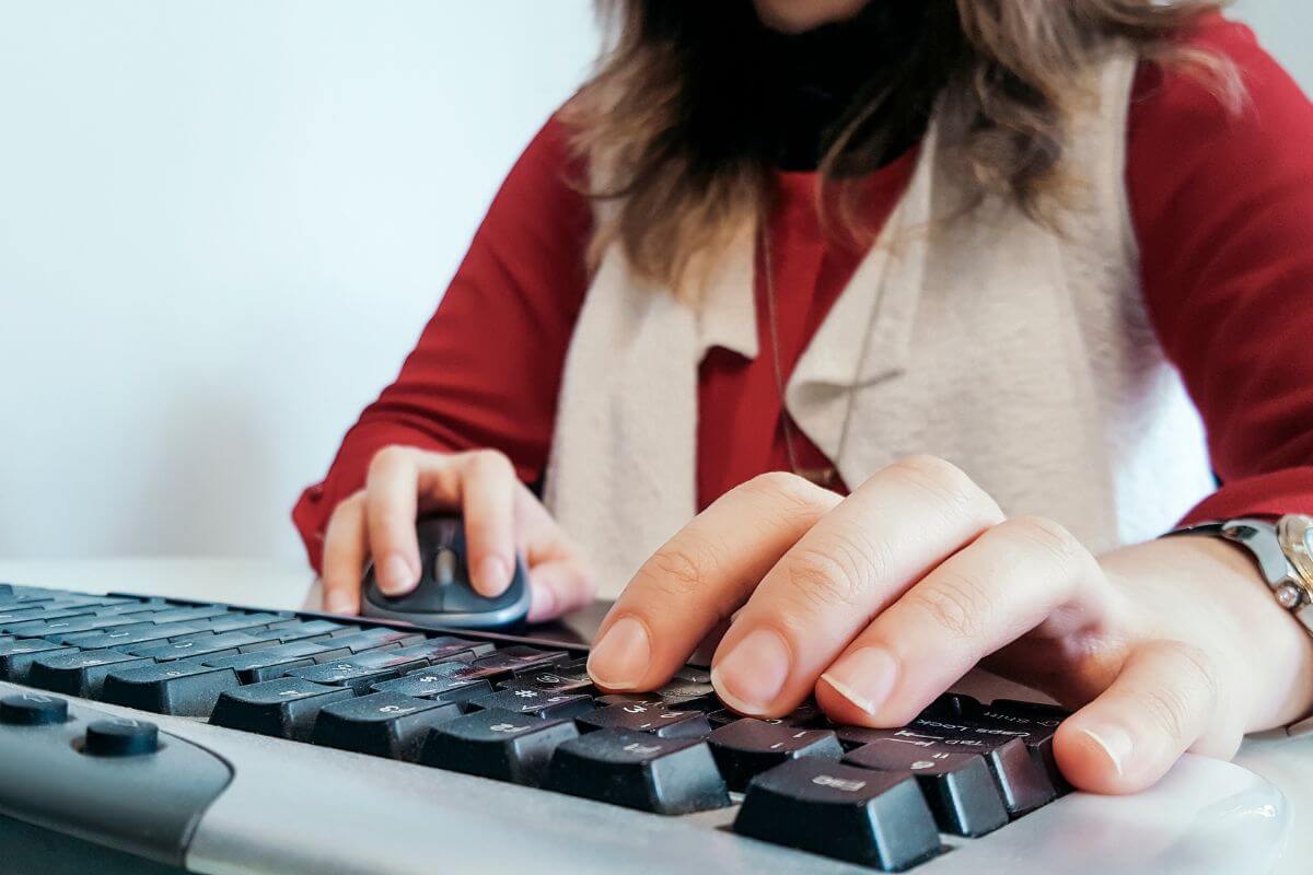 The picture shows a girl's hand typing on a keyboard referring to data entry as one of the easiest remote jobs and an easy way to earn from home.