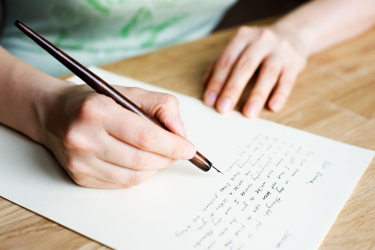 The photo shows a man's hand writing on the paper which means that writing a heartfelt letter shows more love than any store-bought card.