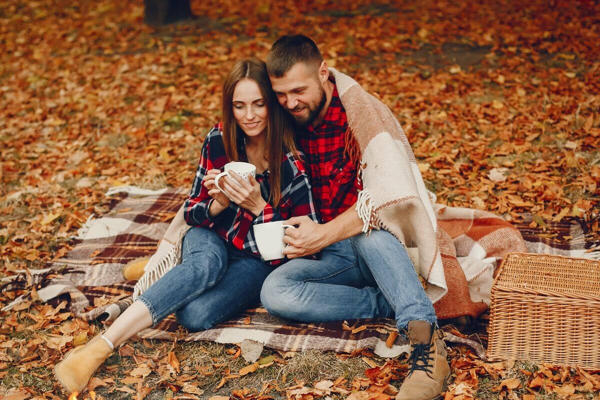 The picture of a basket and a couple sitting on the ground with fabric on while having a coffee refers to going for an experience over things that can be more meaningful than an expensive dinner.