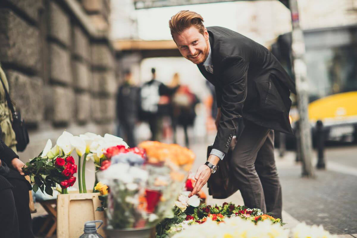 The photo tells about a man picking up flowers on the street vendor referring to buying discounted flowers to keep more money in your pocket.