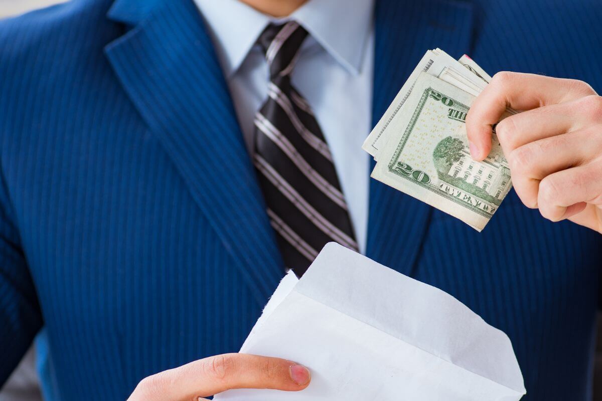 The image shows a man in a suit putting the dollar bills inside the white envelope indicating by 30 aiming for 1x your salary saved that can make a huge impact later.