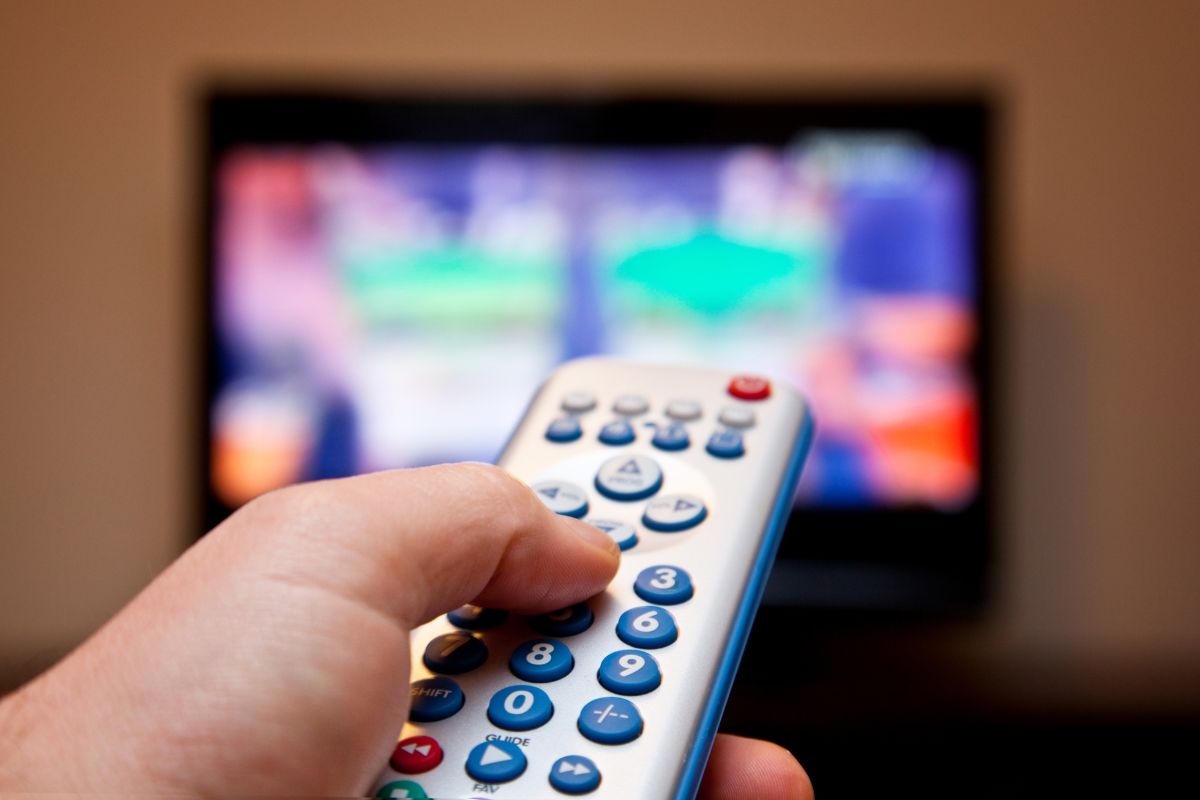 Image of a man's hand watching a TV.