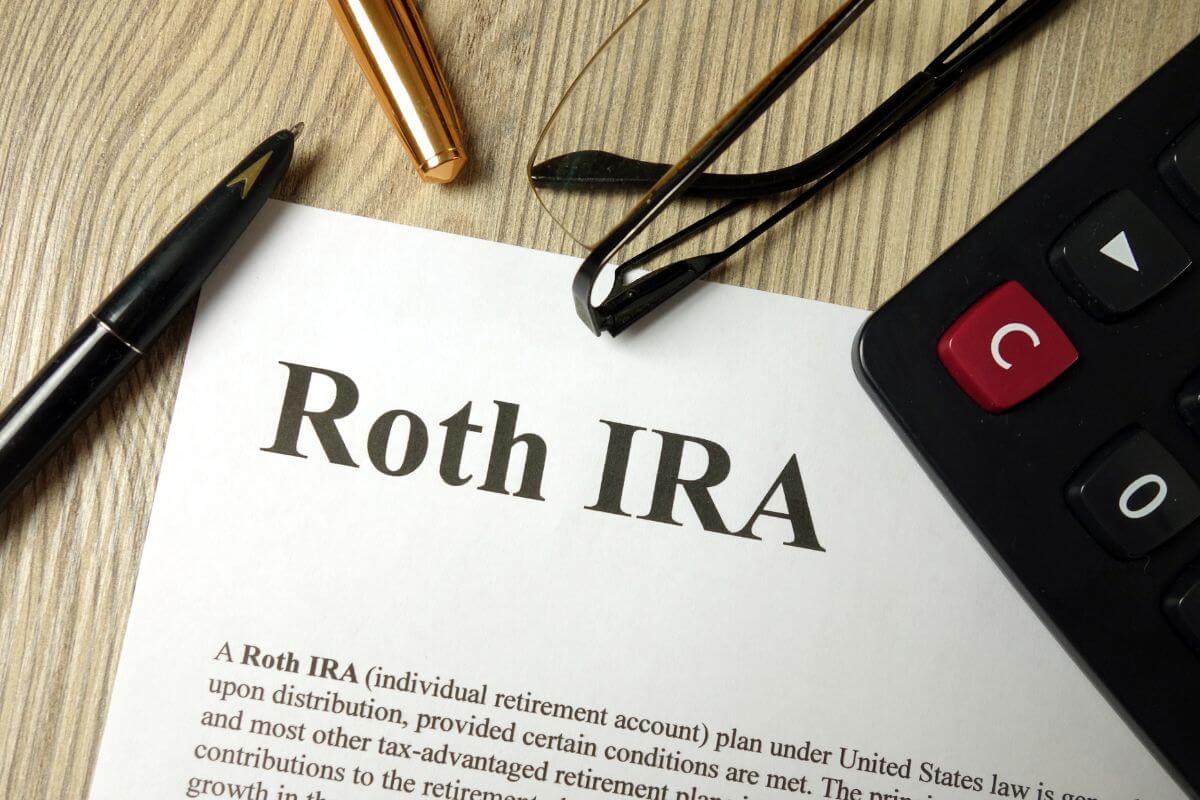 The picture of a calculator, a pen, an eyeglass, and a piece of paper  with notes which means open a Roth IRA in your 20s or 30s to more time your money has to grow.