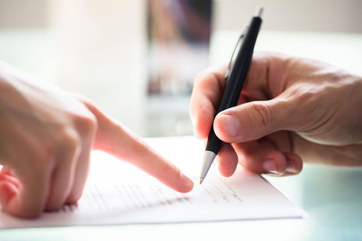 The picture tells about a man's hand signing the paper and a girl's hand pointing it which means negotiate a pay-for-deletion deal with your creditor makes it easier to get loans and better interest rates later.