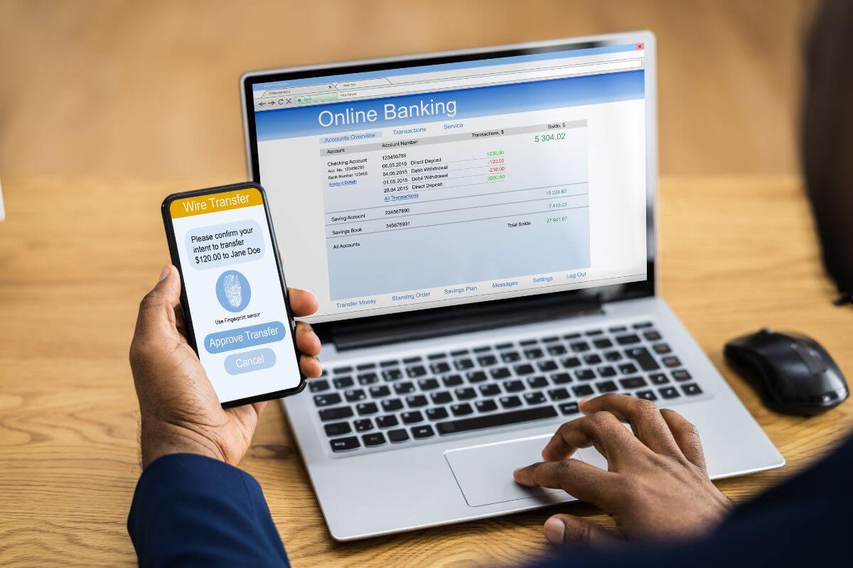 The picture of a man using a laptop with a  screen display and a phone which means switch to 0% APR balance card can stop interest from growing while you pay down debt.