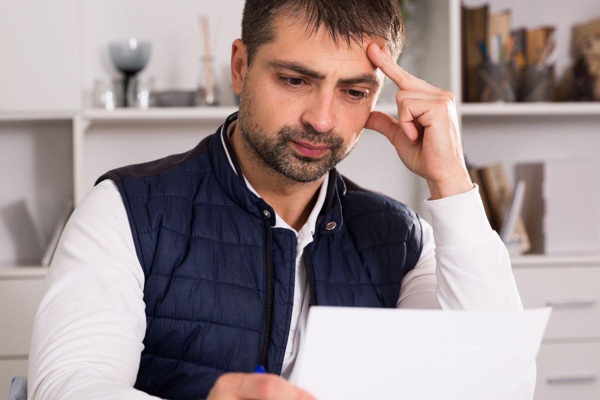 Image of a man's hand looking at the paper.