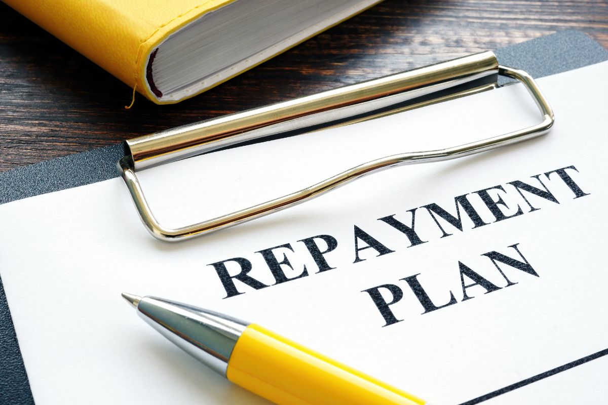 Photo of a pen and paper with repayment plan wording.