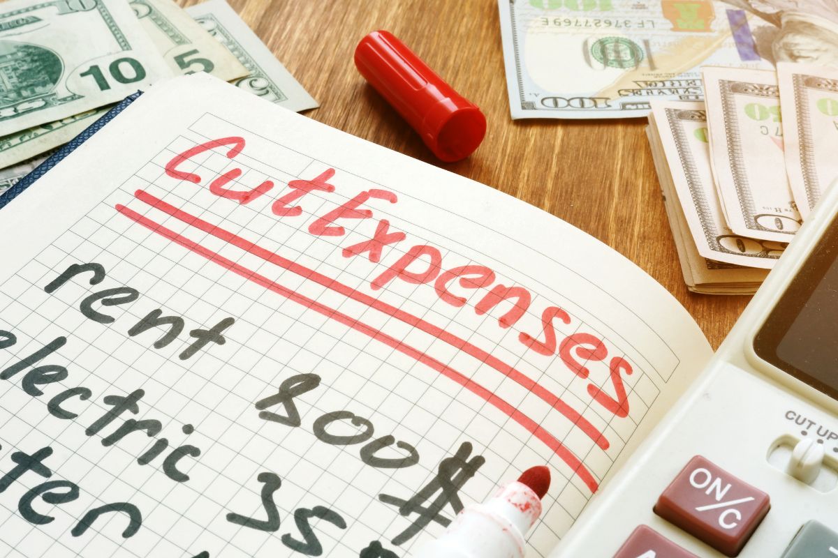 Photo of money and notebook with cut expenses lists.