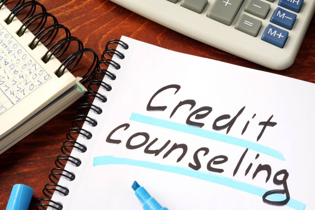 The image shows a calculator, a marker, and notebooks with notes referring to how credit counseling can help if debt feels overwhelming.