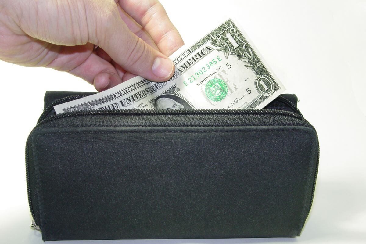 The picture tells about a man's hand adding a 1 dollar bill to his wallet referring to starting today with just $1 that may add up over time that brings you closer to financial security.