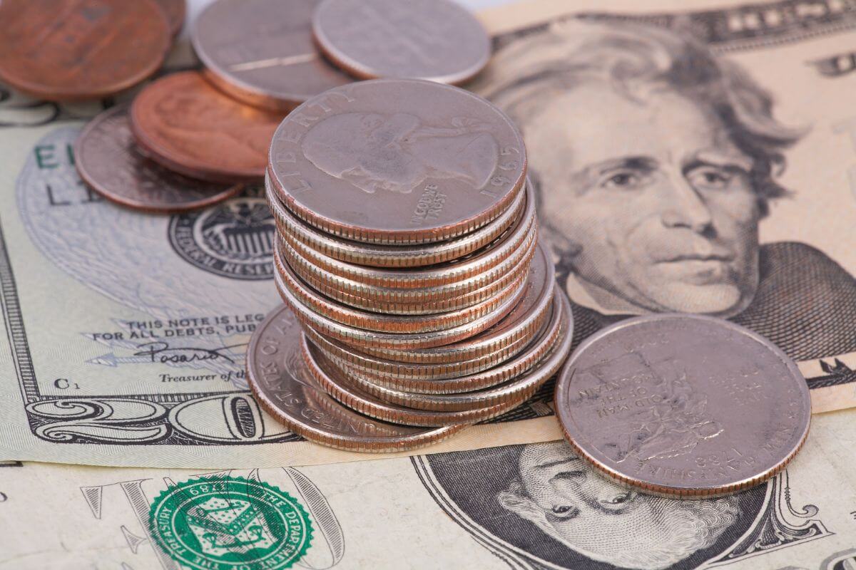 The photo tells about dollar bills and coins indicating to invest spare change with roundup apps take the extra cents from everyday purchases and put them into savings or investments.