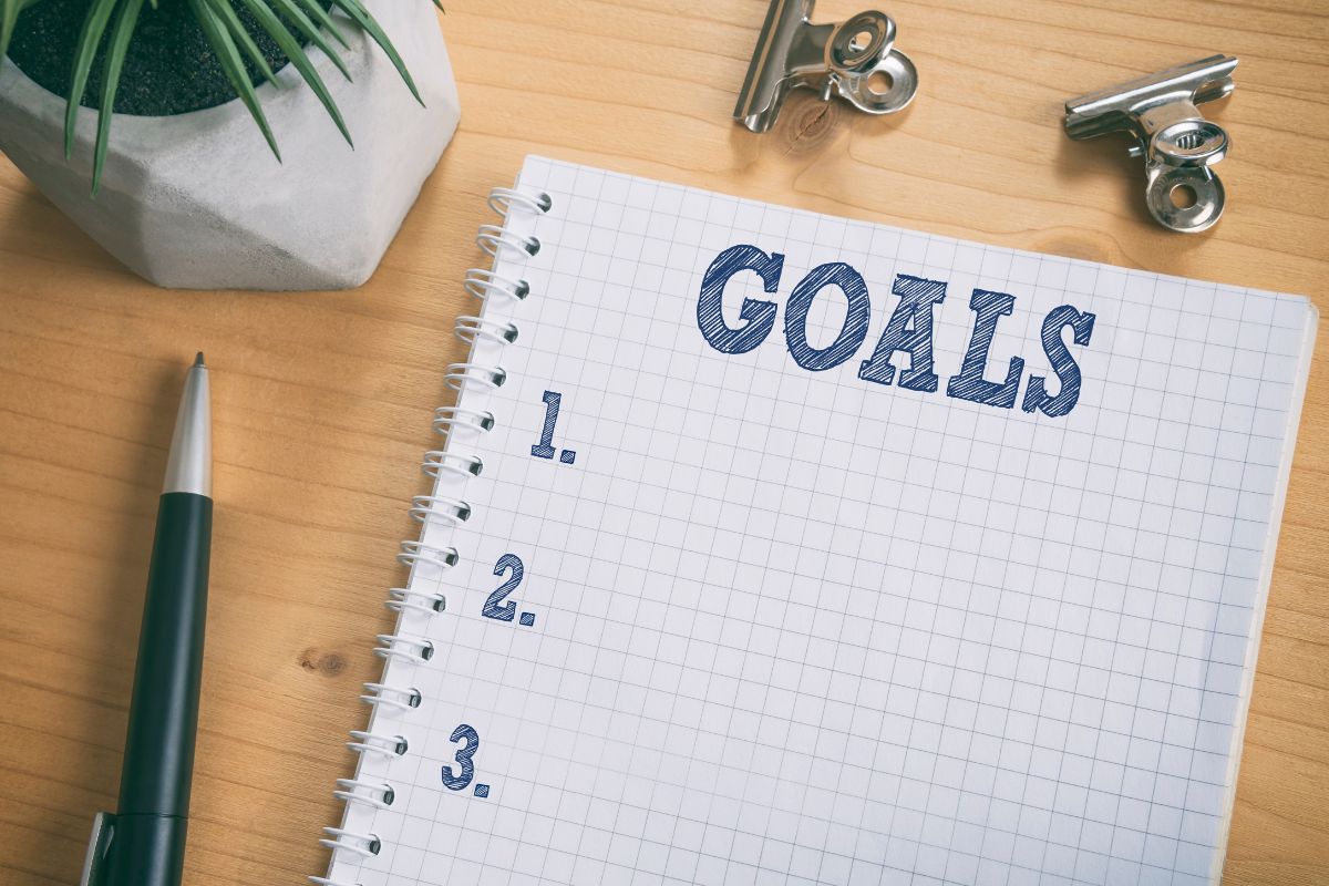 Photo of a pen and a notebook with goal wording.