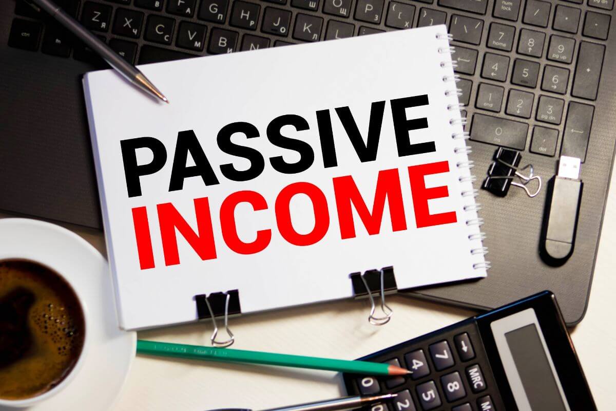 The photo tells about a calculator, a coffee, pens, a laptop, and a notebook with notes referring to creating multiple income streams to earn extra money that adds to your savings.