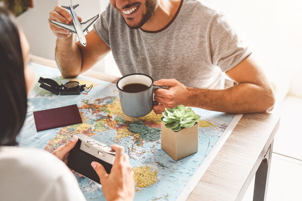 The image shows a plant, a map, a passport, and a couple having a coffee and holding a toy plane and camera which means to plan for major life events to enjoy together the succeeding goals.