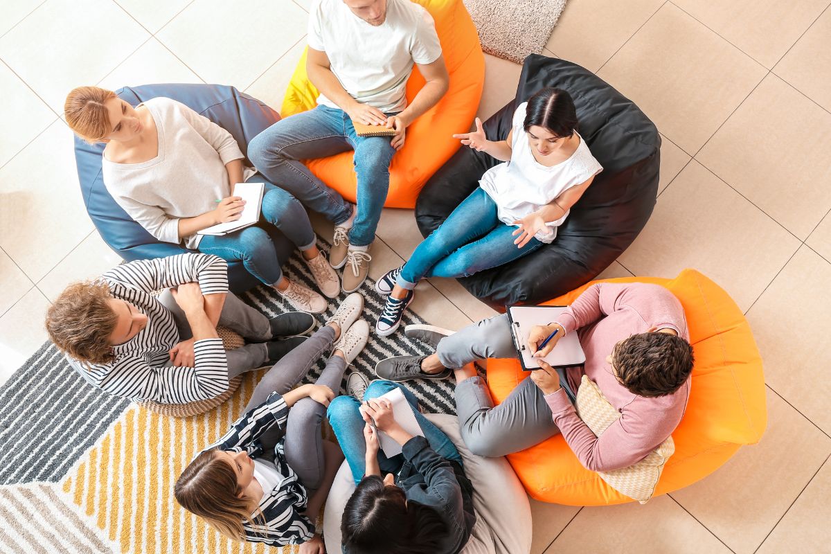 The image shows a group of talking while taking down notes, which means that surrounding yourself with financially savvy people can help you stay on track and make better credit decisions.