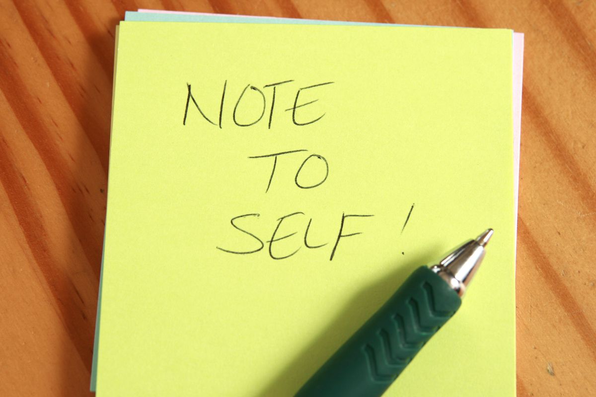 The photo shows a pen and notebook with a Note to self written.