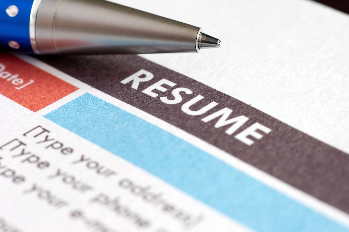 The image shows a pen and piece of paper with notes referring to tailoring each resume with keyword optimization comparing your resume to a job description and suggesting words to add that increase your chances of landing a job.
