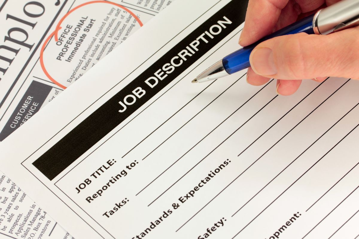 The photo shows a man's hand filling out his job description.