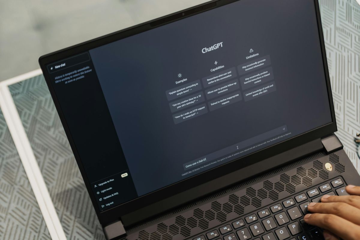 The picture tells about a man's hand using a laptop with a screen display referring to the use of ChatGPT to refine bullet points that can help turn a dull sentence into something that catches attention. 