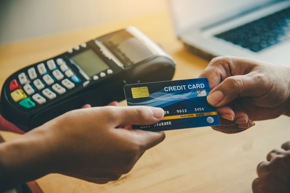 The picture shows a swipe machine and a girl's hand getting the credit card from a man's hand referring to leverage credit card rewards to fun fun purchases to set a limit and avoid overspending