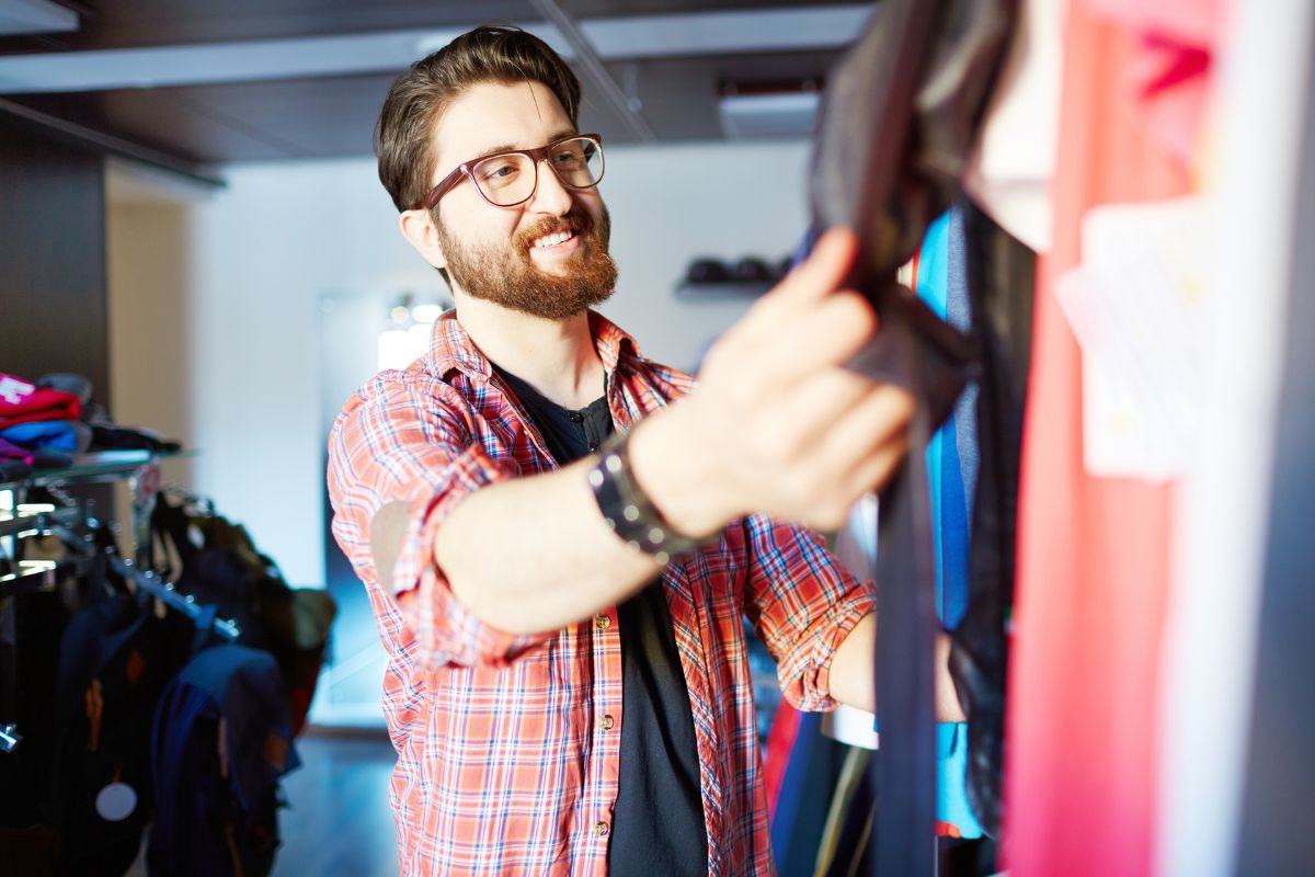 The photo tells about a man picking up clothes at the store referring to applying the joy-per-dollar test by buying a certain stuff that brings long-term happiness to avoid money going to waste. 